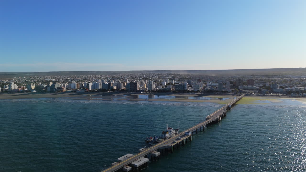 Puerto Madryn bay and pier on Argentina’s Atlantic coast. The scenic view showcases calm waters, vibrant waterfront, and the iconic pier set against a beautiful coastal landscape.