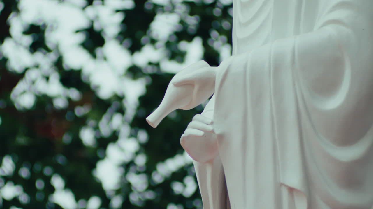 Close-up of the Buddha statue holding a jar, with bokeh in the background