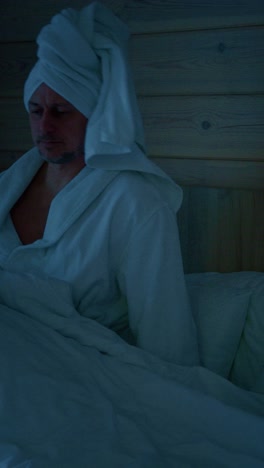 relaxing evening routine with a man in a bathrobe checking his phone in a cozy bedroom
