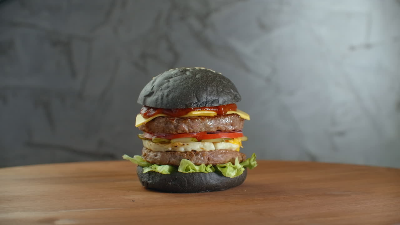 hamburguesa negra de pavo con setas y salsa de setas en una bandeja de piedra negra