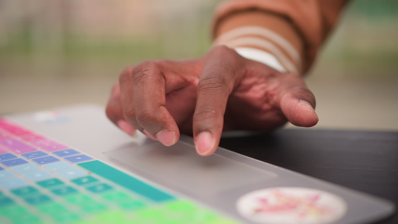 black producer fingertip on colorful pad, focused sample editing in park, morning sunlight on laptop, precise timing and subtle gestures, intimate creative session, tactile sound design
