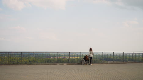 mom and daughter with disability stand on observation deck