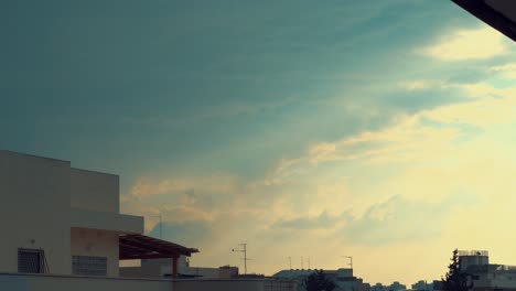 dramatic colorful surfing clouds, blue and yellow sky, building rooftop, time lapse, 4k video