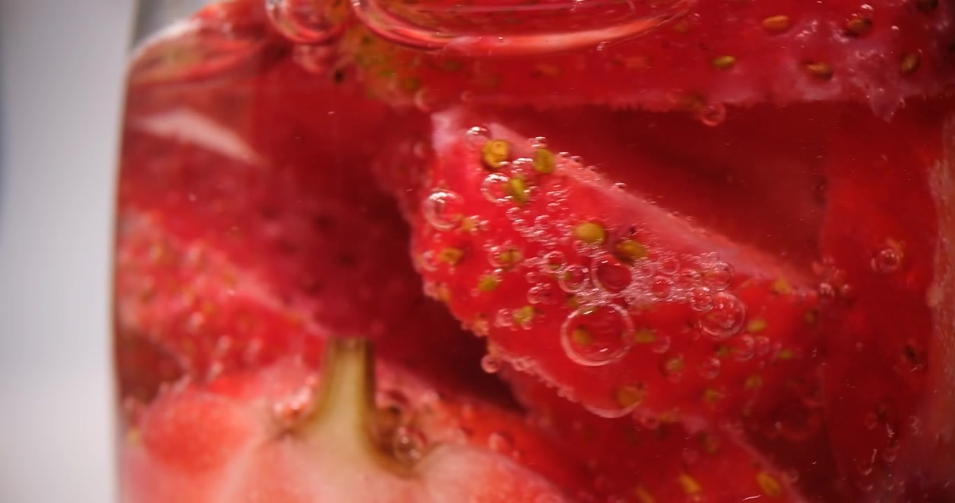 Fragole appena affettate galleggiano in un bicchiere d'acqua trasparente