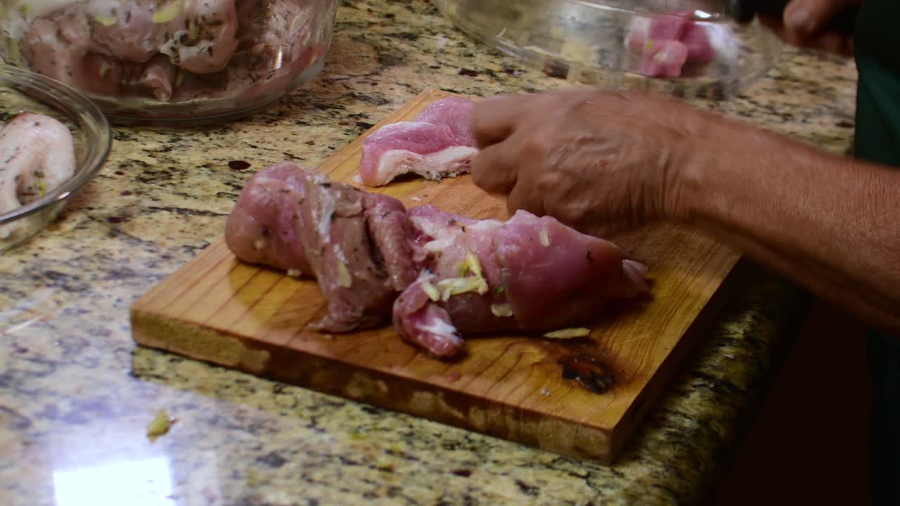 Close-up tangan seorang wanita memotong daging babi di atas talenan di dapur rumah, masakan tradisional, bahan-bahan segar, persiapan otentik buatan sendiri