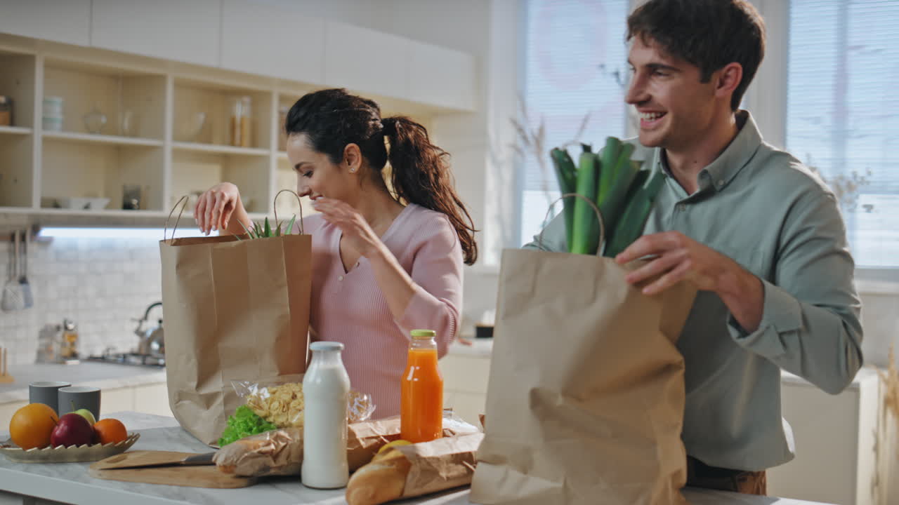 una pareja haciendo compras en la mesa de la cocina desde la tienda de comestibles. cónyuges felices.