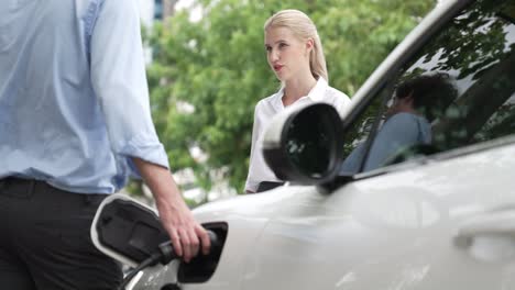 Progressive-businessman-and-businesswoman-use-charging-station-for-EV-car.