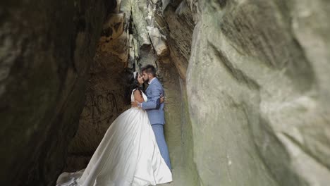 Groom-with-bride-standing-in-cave-of-mountain-hills.-Wedding-couple-in-love