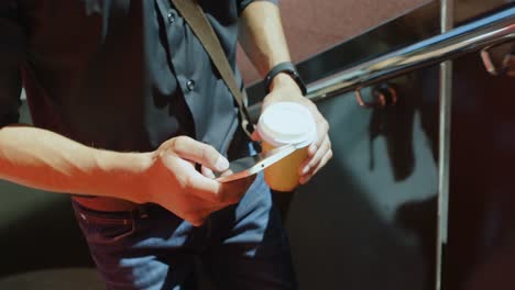 hombre con taza de café usando teléfono móvil mientras camina 4k