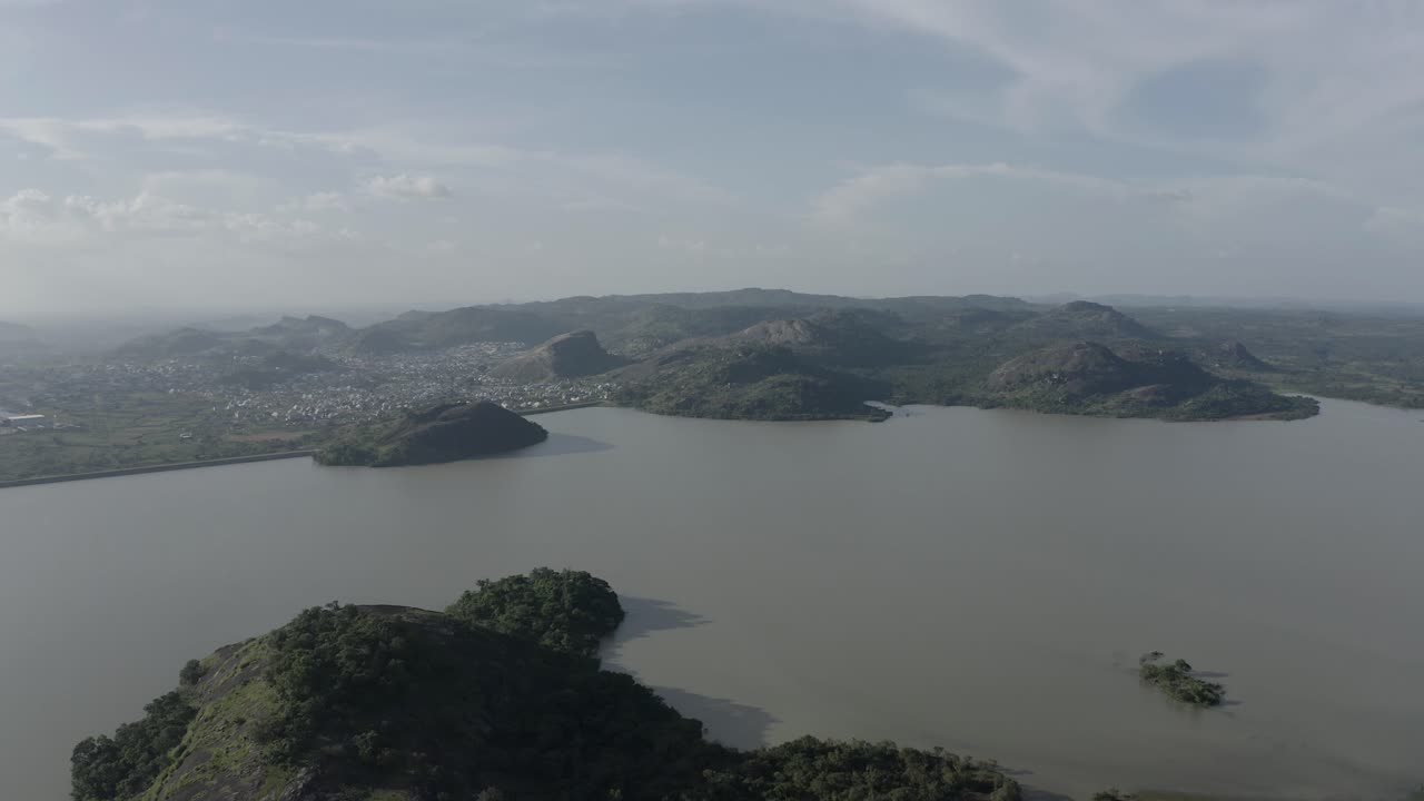 무성한 오아시스의 항공 샷으로 산으로 둘러싸인 해안 커뮤니티를 보여줍니다.