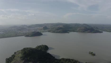 Toma-Aérea-De-Un-Exuberante-Oasis-Que-Revela-Una-Comunidad-Costera-Rodeada-De-Montañas