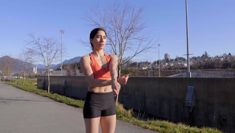 sporty woman stretching arms across body in workout clothes