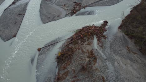 Aerial-shot-tilting-down-overlooking-excess-rain-water-channeling-its-way-down-a-river-bed,-recent-flooding-caused-extensive-damage-washing-up-sand-and-debris-in-Chilliwack,-British-Columbia,-Canada