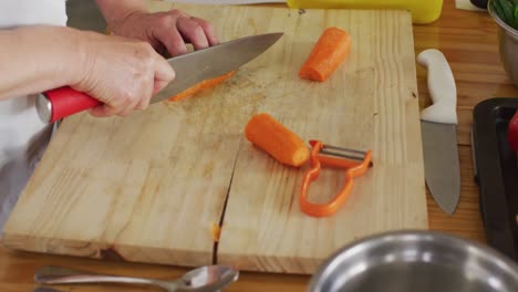 Caucasian-female-chef-cutting-carrots-in-kitchen