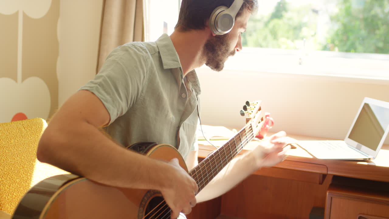 hombre tocando la guitarra acústica en casa