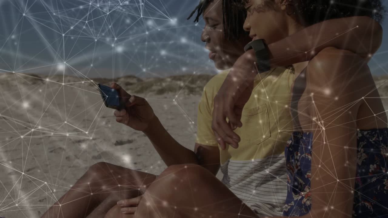 Couple lowering phone from selfie, pointing and sharing pic with network overlay on beach for tech