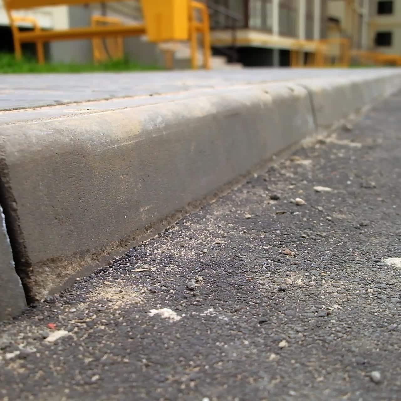 Asphalt road and brick-laid sidewalk near the residential building. Area near the new block of flats. Close up. Blurred backdrop