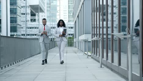 slow motion of two focused managers walking near office building