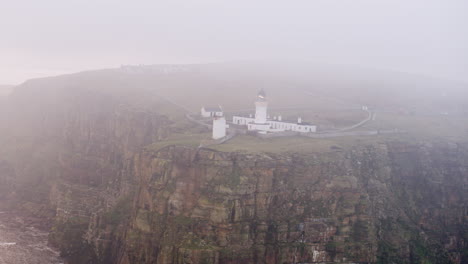 Aerial-shot-of-a-clifftop-lighthouse-on-a-misty-morning-in-the-north-of-Scotland