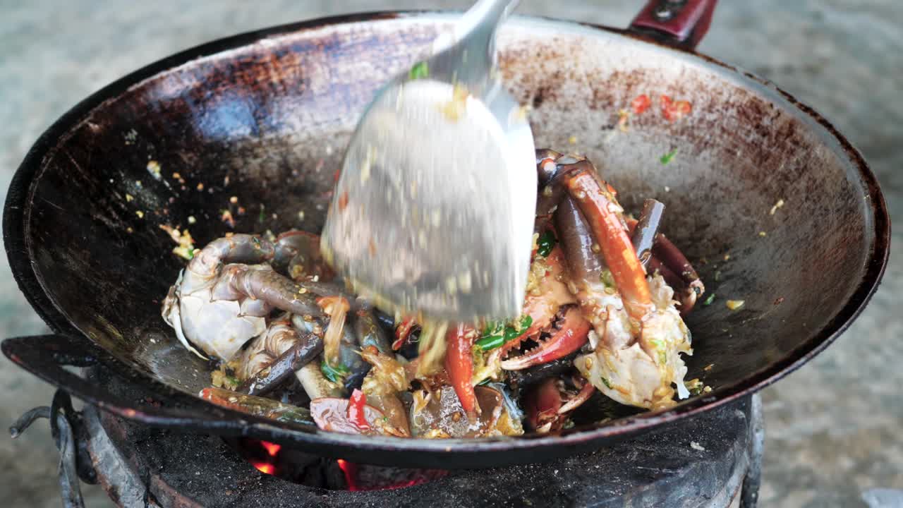 Cooking fresh crab meat in wok style pan over charcoal fire