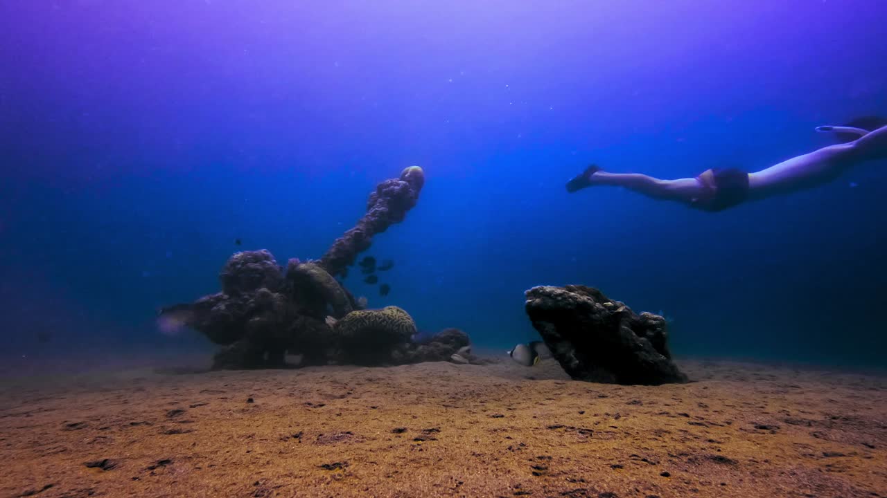 freediver hombre nadando en el fondo del océano encima de un ancla sumergida