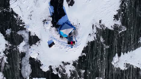 winter ice fishing with tents and snow blowing across lake geneva wisconsin, slow motion aerial top shot static