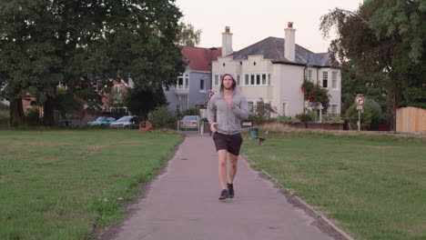 young athletic man goes for a run in the park, runs towards camera in slow motion