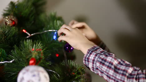 Child Dresses Up The Christmas Tree. Happy little kid decorate Christmas tree in beautiful living room