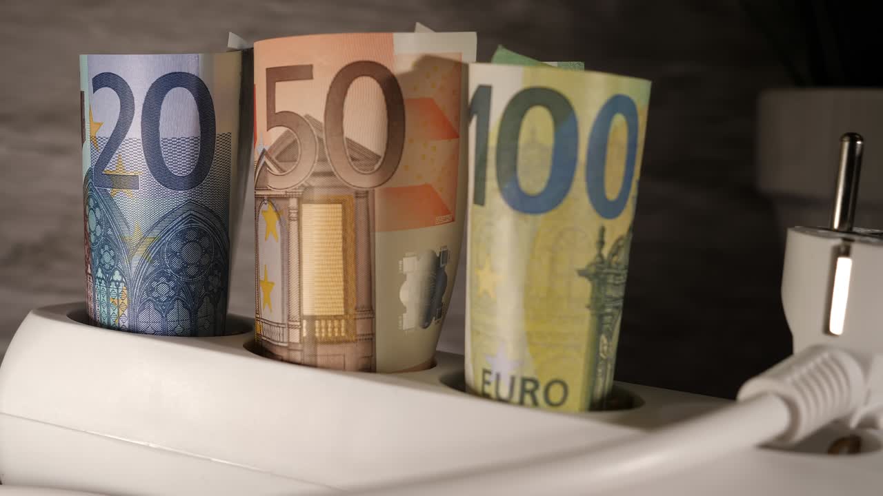 un primer plano de euros y un enchufe que muestra el concepto de alto precio de la energía.