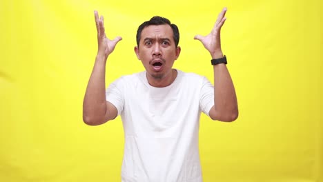 a shocked asian man standing while touching his head and looking above isolated over yellow background in studio