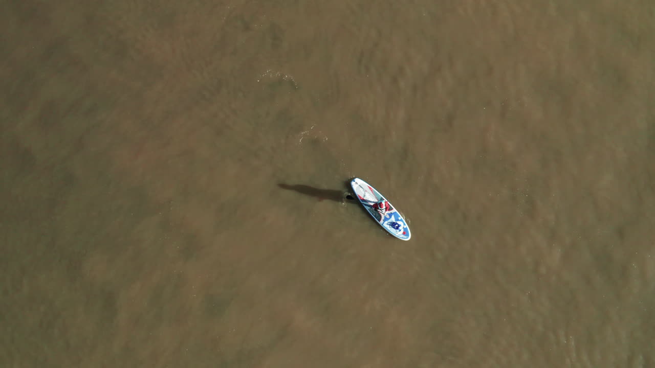 persona solitaria con traje de santa claus en stand up paddle board en la laguna de obidos, portugal