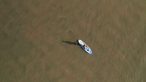 persona solitaria con traje de santa claus en stand up paddle board en la laguna de obidos, portugal