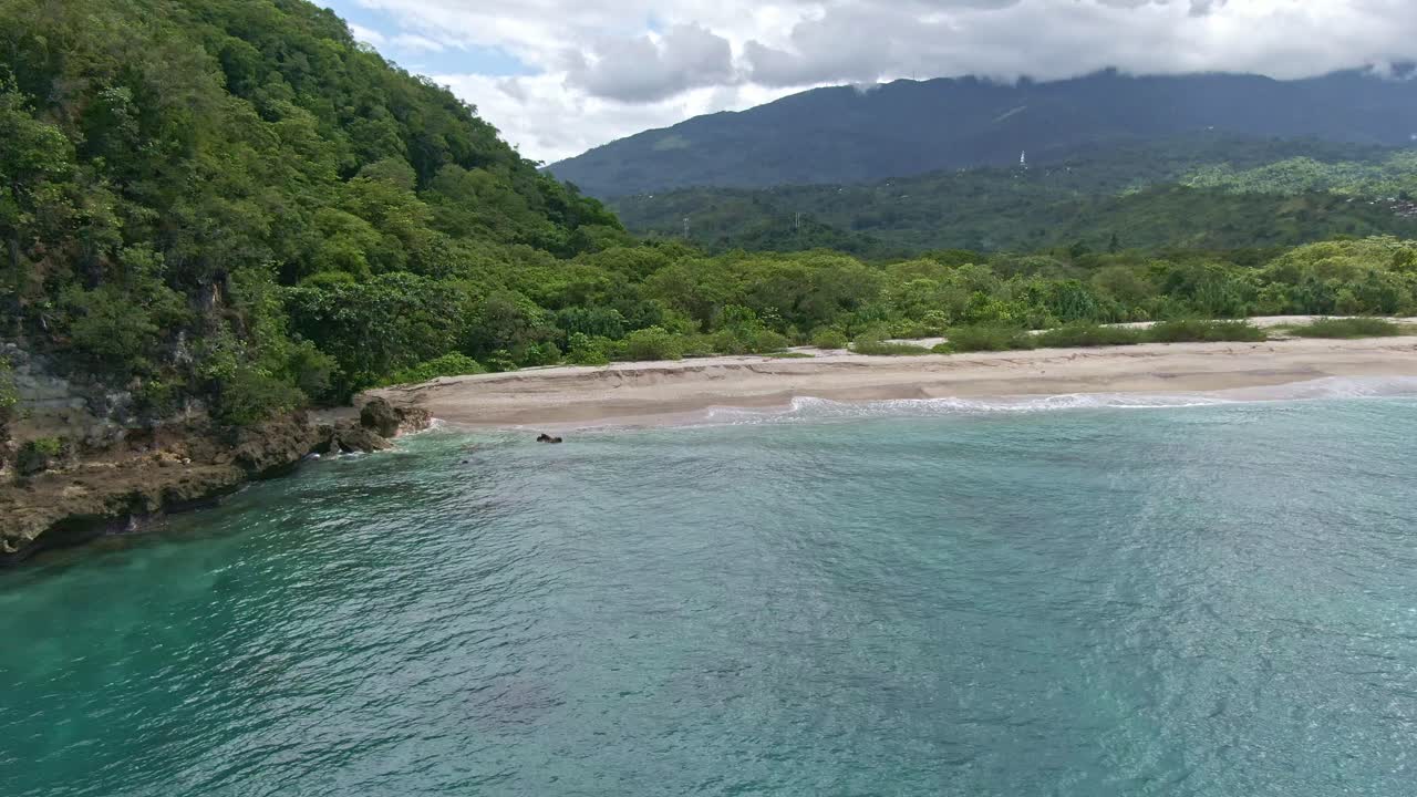 paisaje increíble vista cinematográfica de la playa blanca a través de la arena de la costa y olas rompientes, fondo épico de montañas de silueta con nubes de anillo que lo rodean