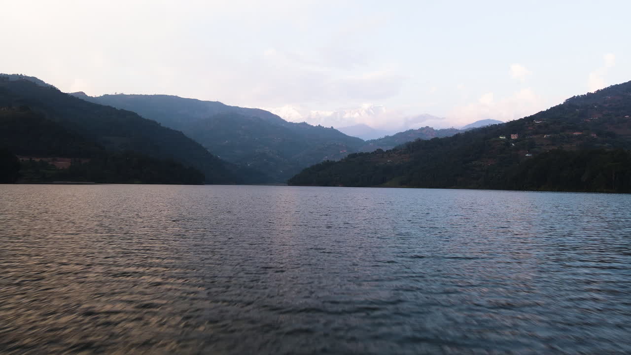 A Serene Vista of Phewa Lake Framed by the Himalayan Mountains at Sunset in Pokhara, Nepal - Drone Flying Forward