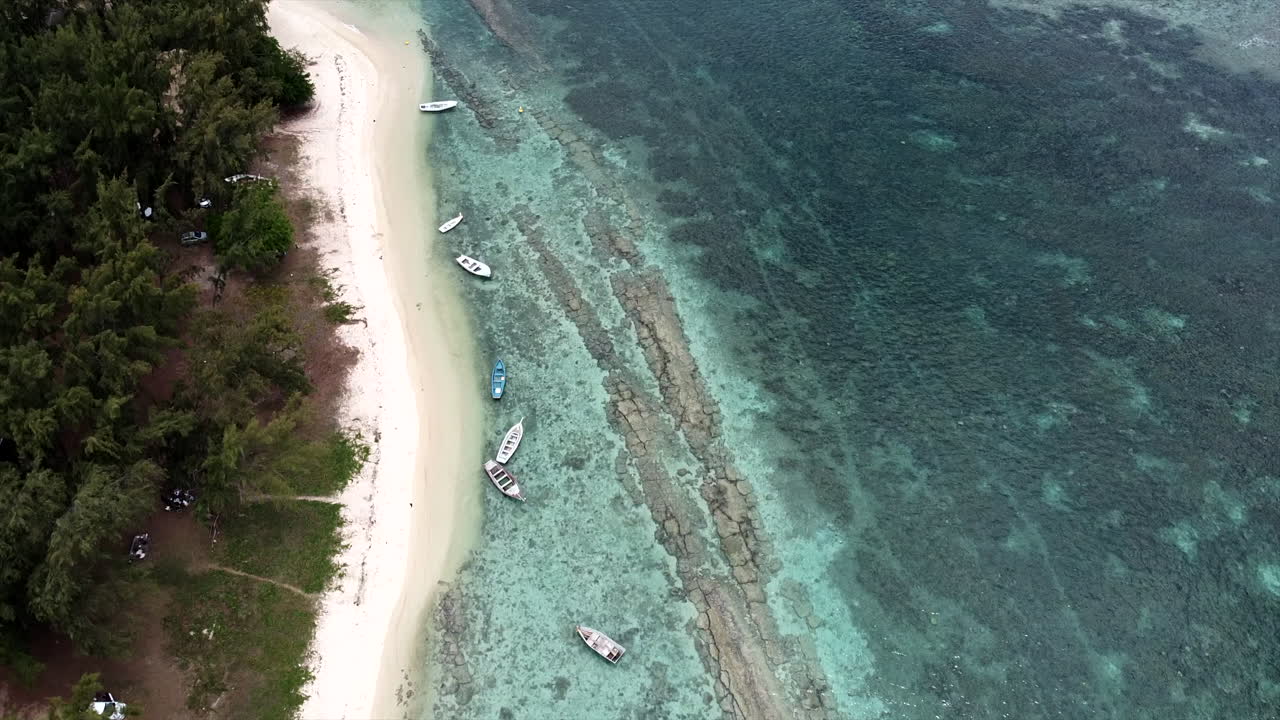 황금빛 해변과 맑은 물에서 수영하는 보트가 있는 이국적인 섬의 느린 공중 촬영