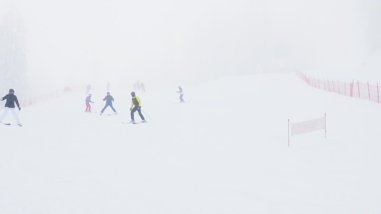 Skiers on a foggy ski slope