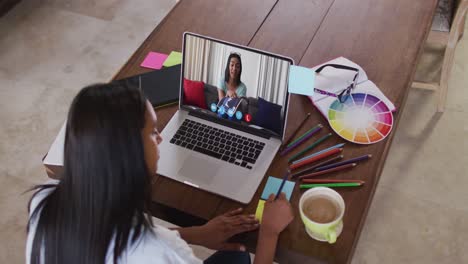 Eine-Afroamerikanische-Frau-Macht-Sich-Notizen,-Während-Sie-Zu-Hause-Einen-Videoanruf-Mit-Einer-Kollegin-Auf-Dem-Laptop-Führt