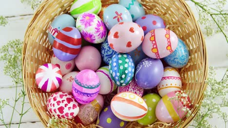 cesta con huevos de pascua pintados en superficie de madera