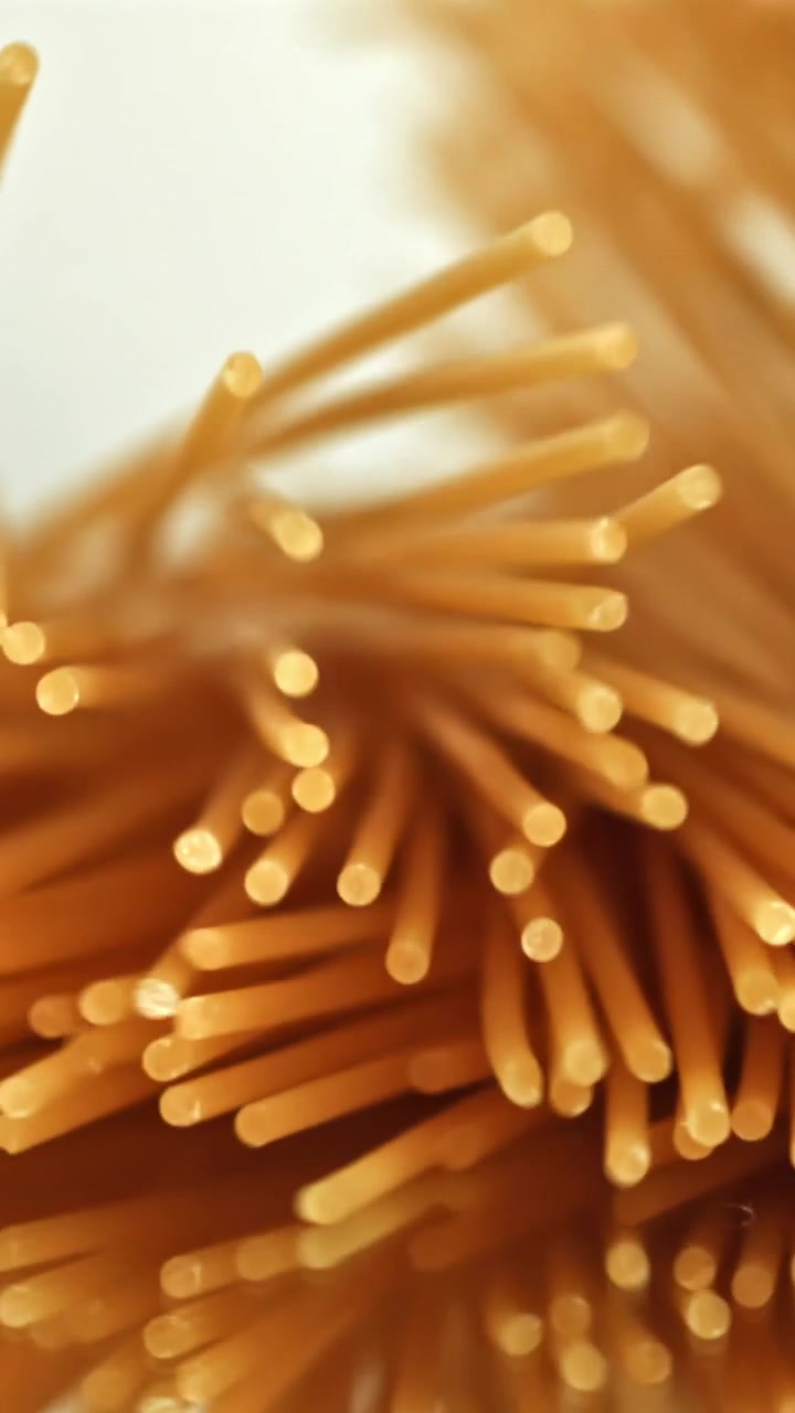 Primo piano di spaghetti secchi che cadono su una superficie riflettente
