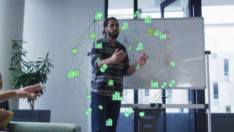 Animation-of-globes-of-financial-icons-spinning-against-biracial-man-giving-a-presentation-at-office