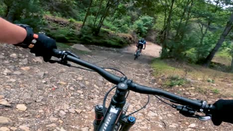 Two-bicyclists-ride-their-bicycle-on-a-road-inside-of-a-forest,-hill,-and-village-in-Guatemala,-North-America