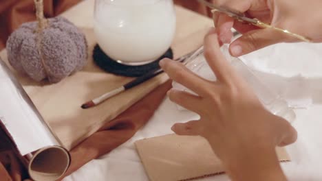 hands using scissors in cutting plastic bottle in a recycling craft project on a table with a cozy autumnal mood setup