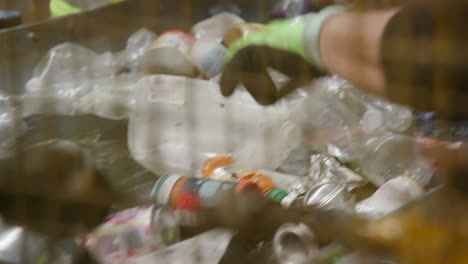 personas clasificando botellas de plástico y latas de aluminio en una cinta transportadora en una planta de reciclaje