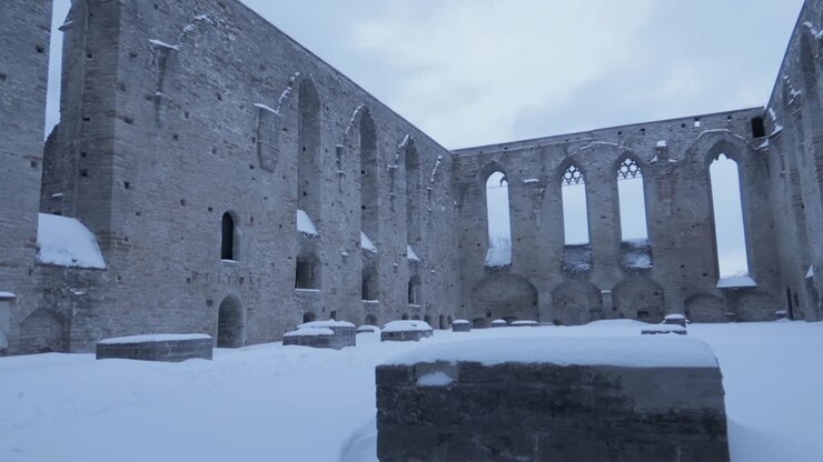 Ancient church ruin with tall stone walls no roof and snow covering everything during a cold winter day