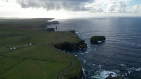 Acantilados-Junto-Al-Mar-Con-El-Sol-Asomándose-A-Través-De-Las-Nubes,-Irlanda,-Vista-Aérea