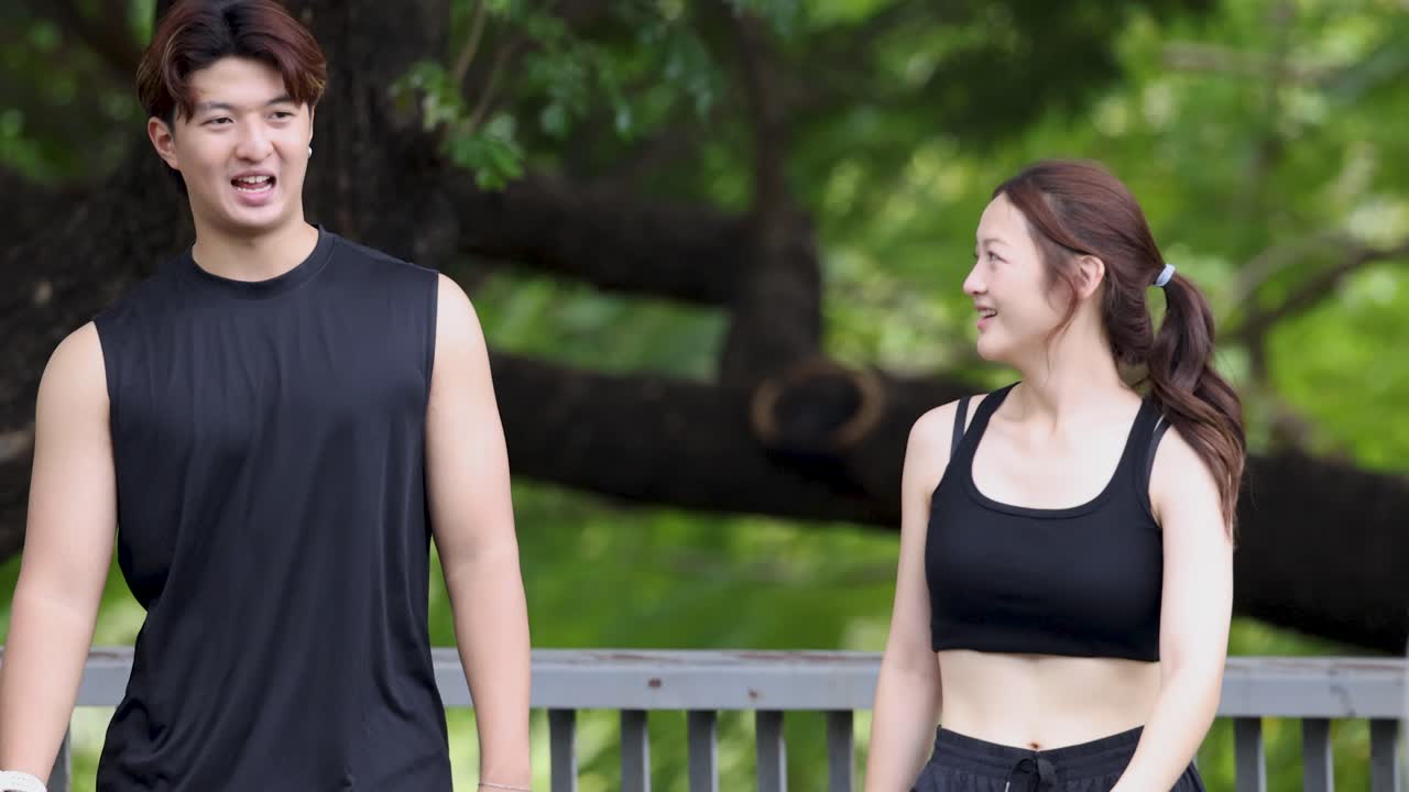 若い男女が緑豊かな公園を散歩しながら、親しげに会話をしています。