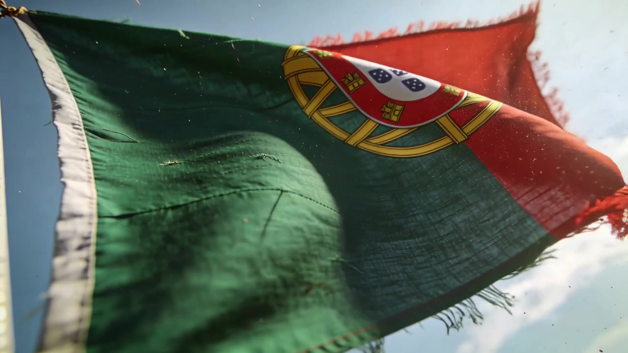 Bris lyfter Portugals flagga på stång under blå himmel, visar emblem, sydd fåll, solbelyst damm