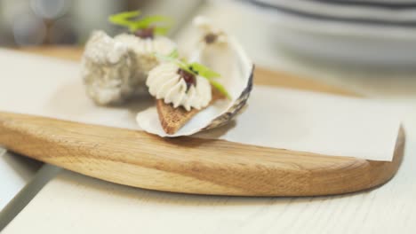 oysters on a wooden tray decorated with small appetizing snacks