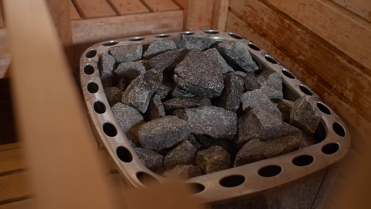 vista de una sauna tradicional con agua salpicada de piedras calientes dentro de una sauna vacía