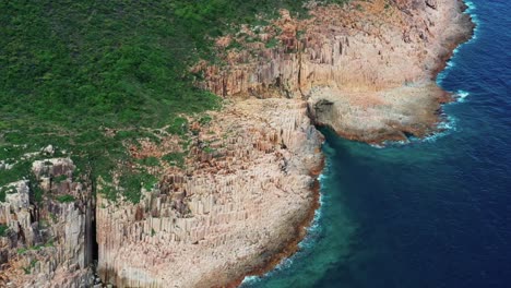 Birdseye-Luftbild-Von-Wellen,-Die-Gegen-Die-üppige-Tropische-Küstenlinie-Der-Insel-Sai-Kung-Schlagen,-Die-Sich-Nach-Unten-Neigt